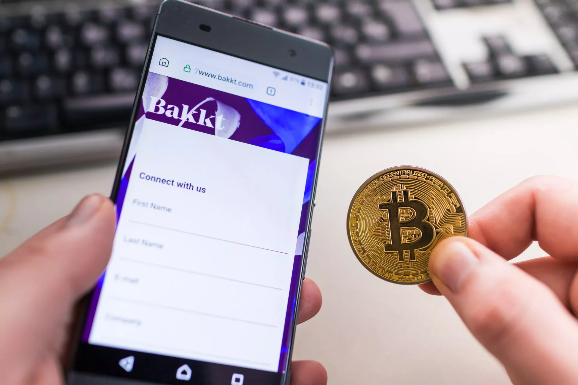 Holding Bitcoin coin with Bakkt website