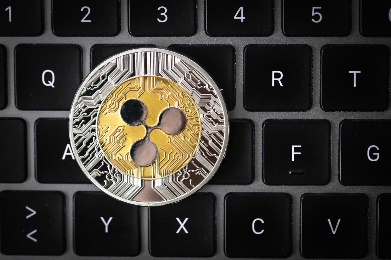 Ripple cryptocurrency, physical coin laying on a laptop keyboard