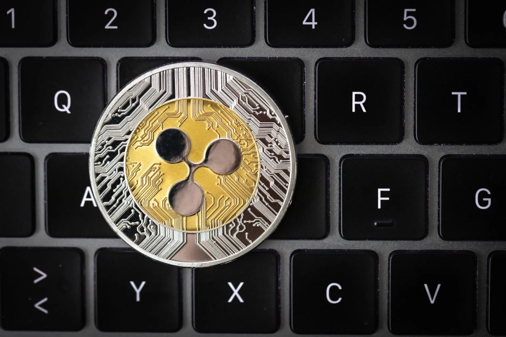 Ripple cryptocurrency, physical coin laying on a laptop keyboard
