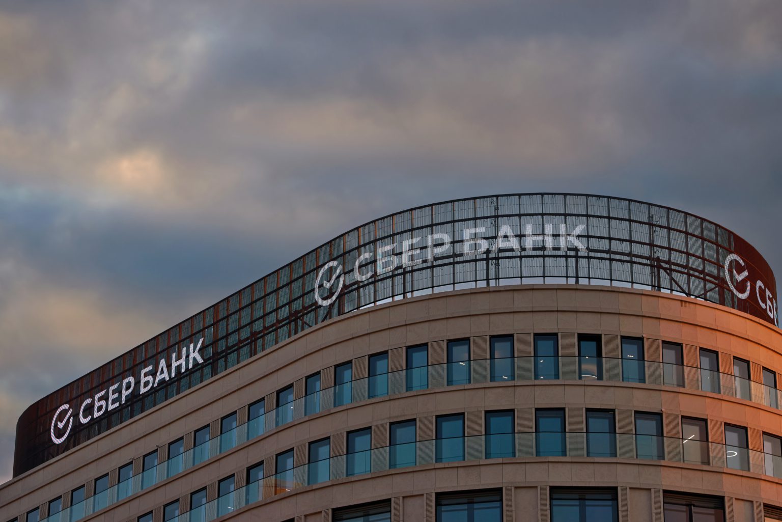 Sberbank-logo in Cyrillisch op glazen gevel van rond kantoorgebouw