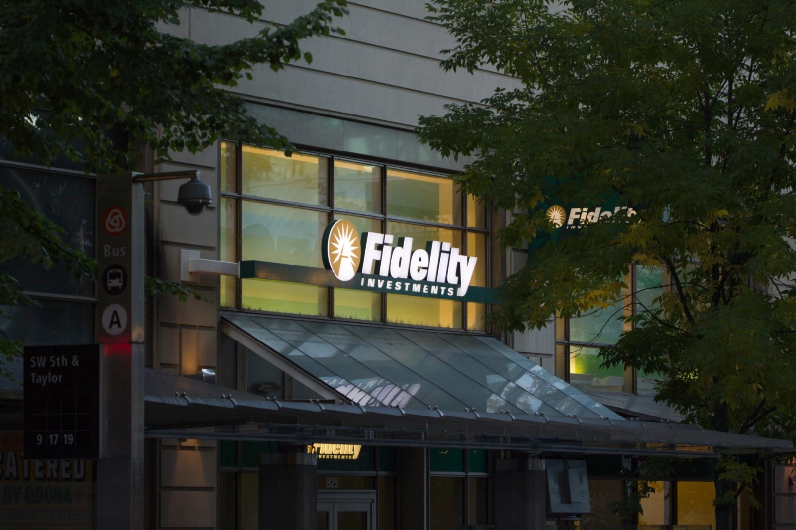 Fassade von Fidelity Investments mit beleuchtetem Logo bei Abendlicht in städtischer Umgebung