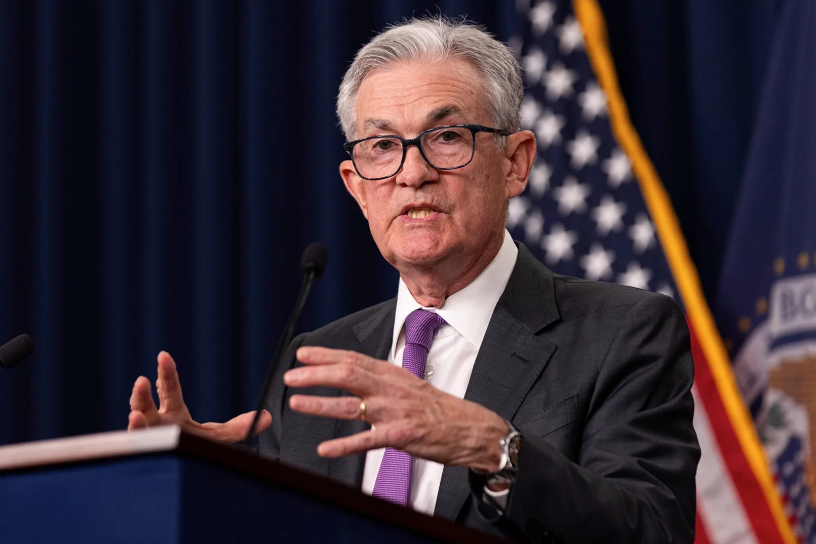Jerome Powell s'exprimant lors d'une conférence de presse avec le drapeau américain en arrière-plan