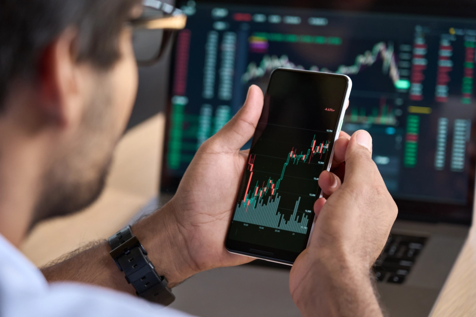 Trader devant un graphique de cours sur téléphone et ordinateur portable
