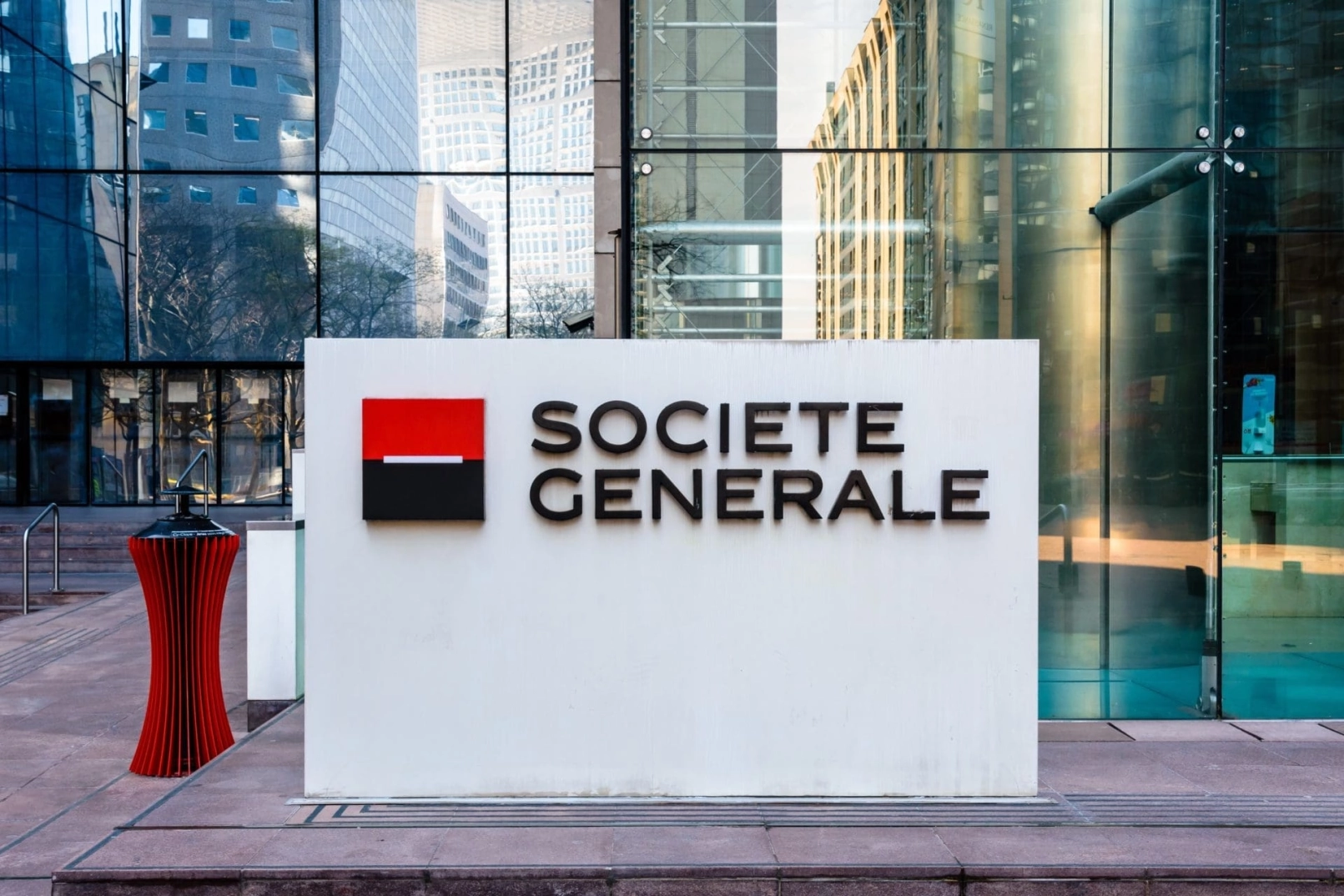 Logotipo de Societe Generale en cartel blanco frente a edificio de oficinas con fachada de cristal