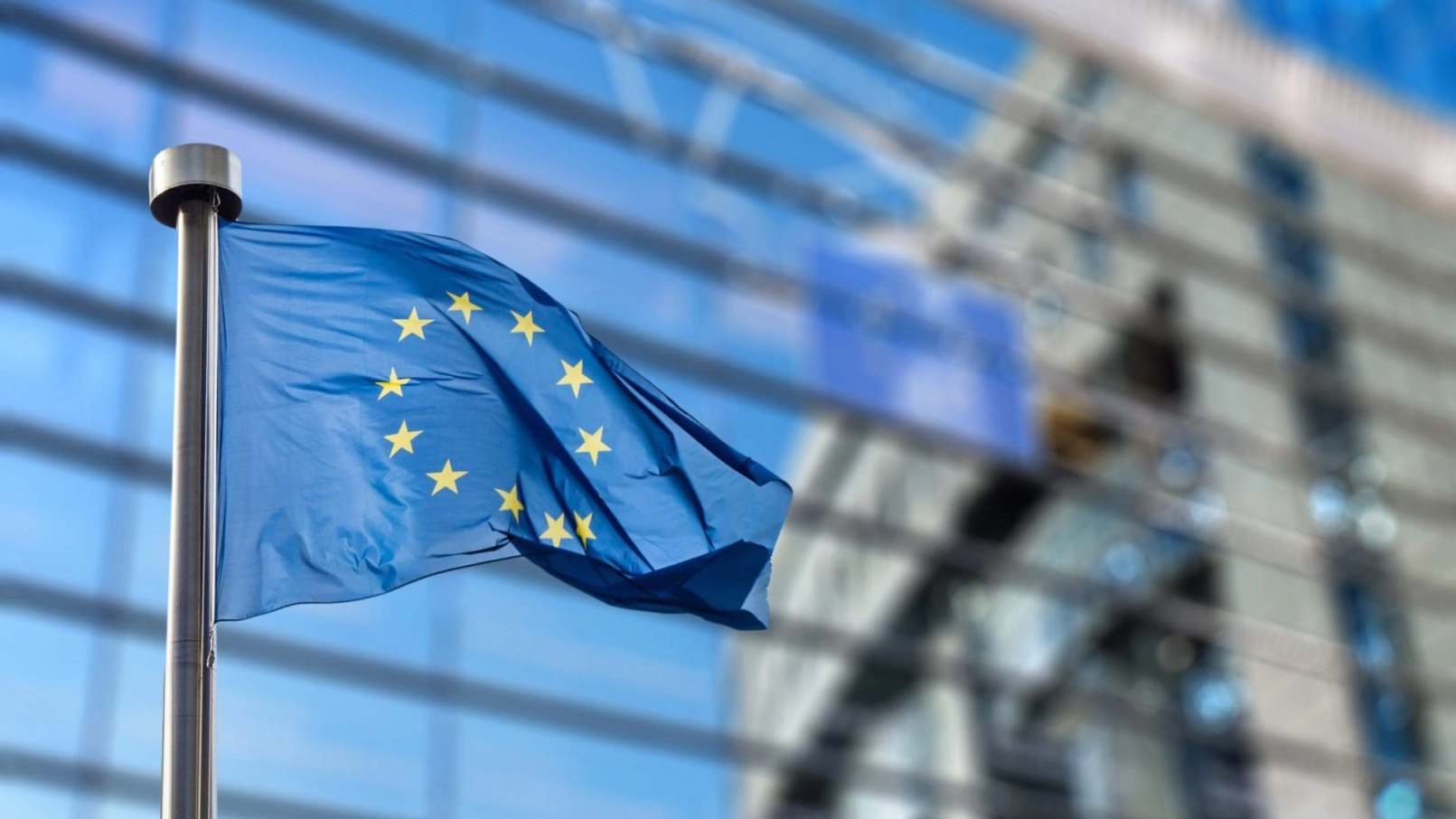 Bandera de la UE ondeando frente a un moderno edificio acristalado del Banco Central Europeo